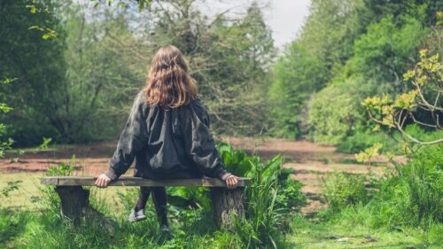 Woman sitting on bench by pond 54321 Grounding Technique aware of senses