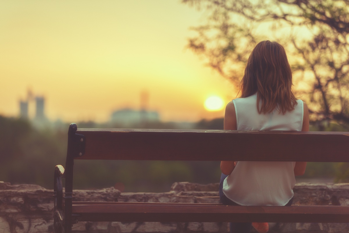 Woman sitting on a bench and watching the distant city scenery.
